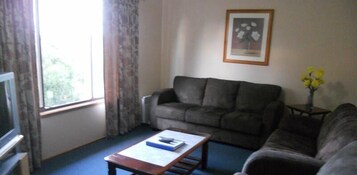 Una sala de estar con un sofá, una mesa de centro, un televisor y un cuadro en la pared.