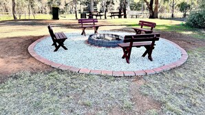 Un parc doté d’un espace circulaire avec des sièges disposés autour d’un foyer, ainsi que de bancs et de tables de pique-nique.