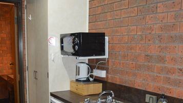 A compact kitchenette with a microwave, coffee maker, and a small refrigerator.