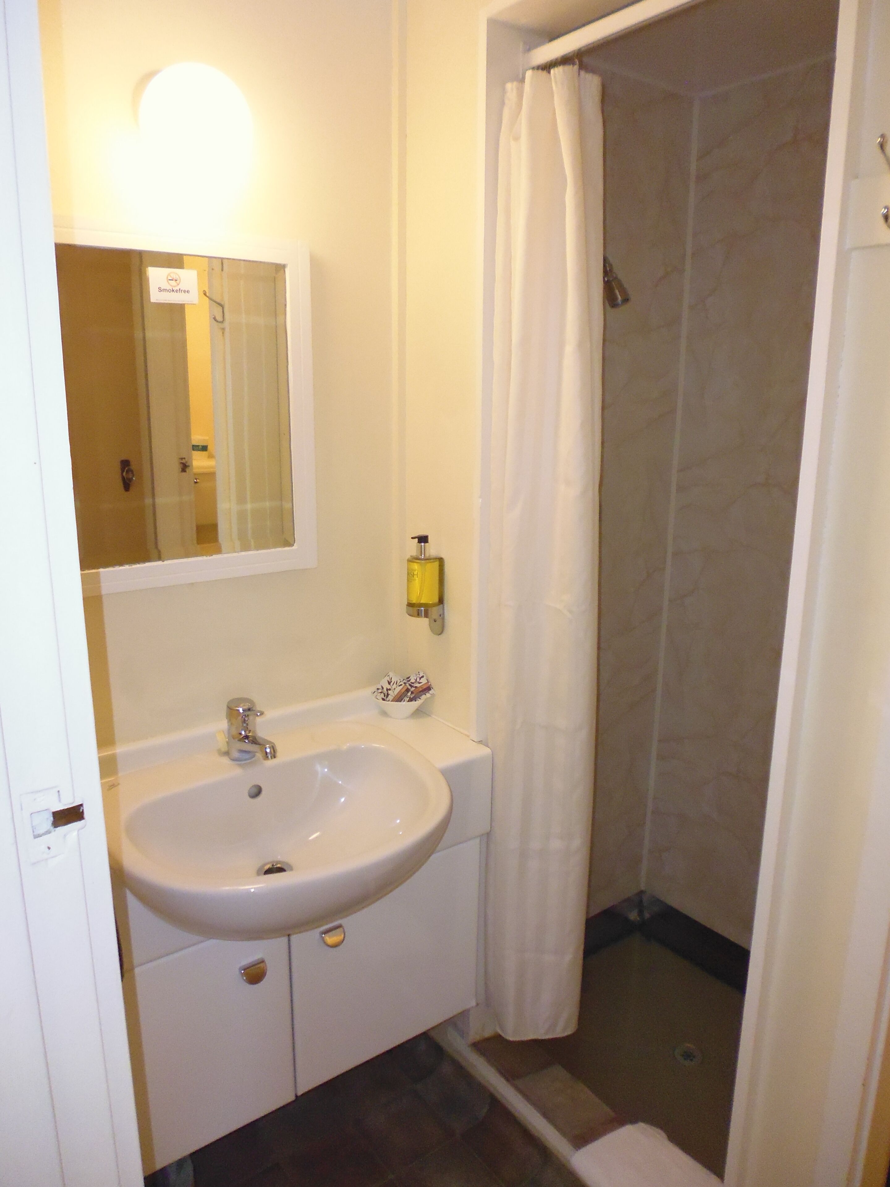 Ein Badezimmer mit Waschbecken, Spiegel und Dusche.