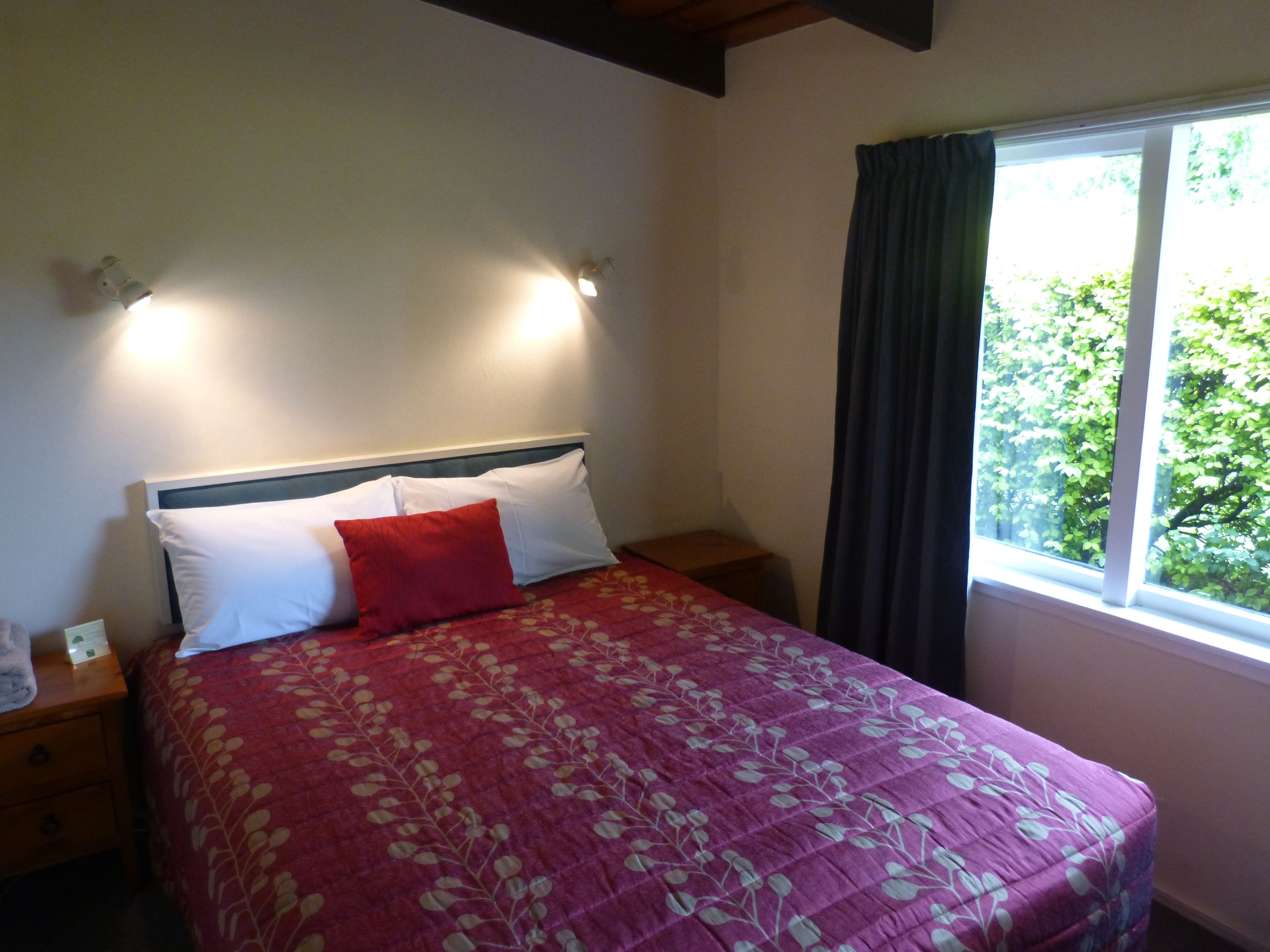 A neatly made bed with a floral-patterned bedspread, two pillows, and bedside lamps.