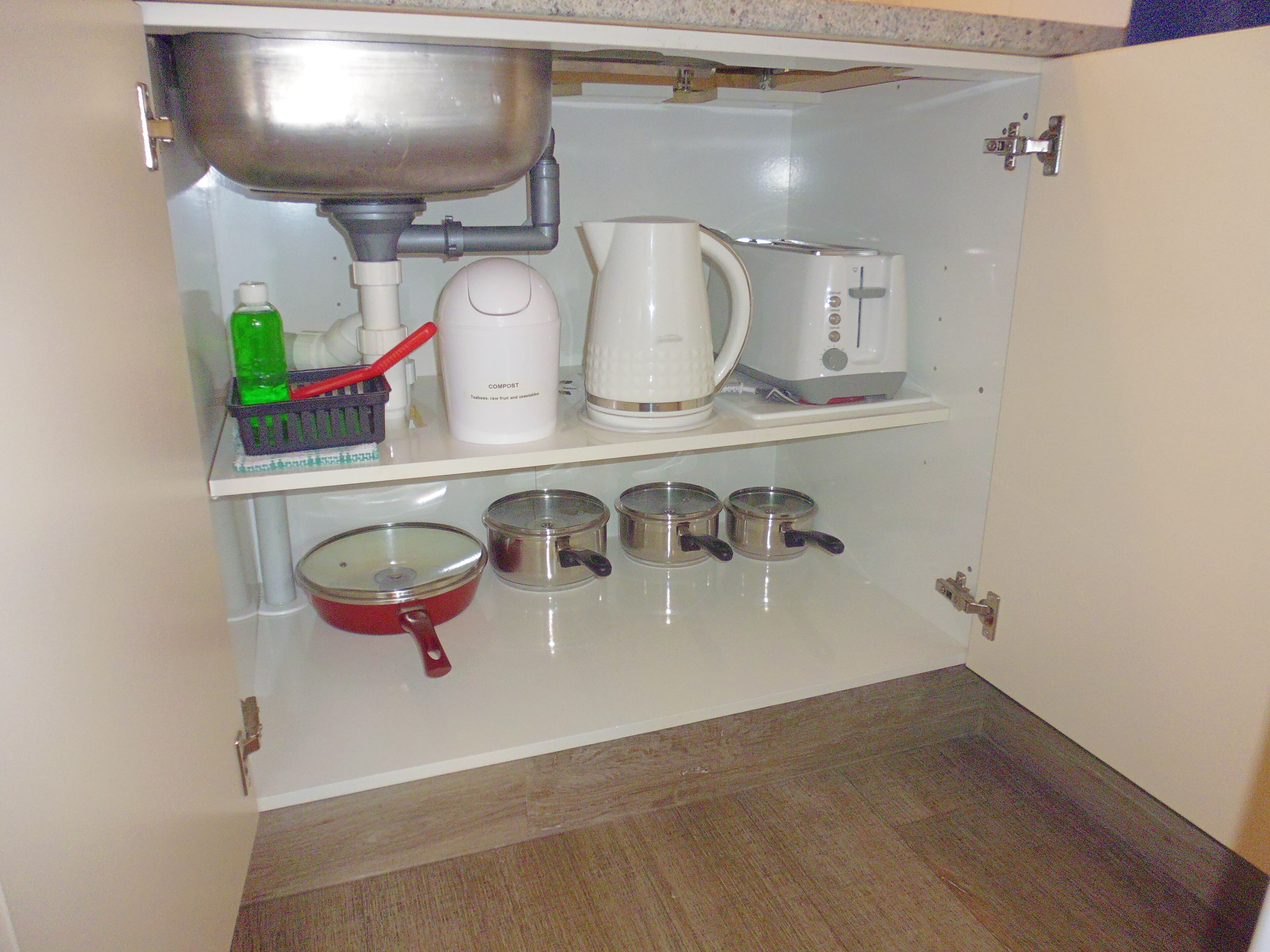 A kitchen with a sink, a kettle, a toaster, and pots on the counter.