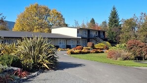A two-story motel with a central entrance, a parking area, and a landscaped garden with various shrubs and plants. - Spa Lodge Motel (Hanmer Springs)
