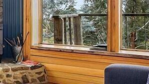 Una habitación acogedora con chimenea de piedra, televisión y ventana con vistas a árboles.