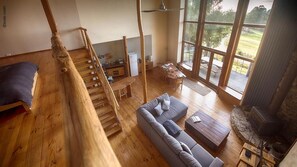 A spacious living area with a wooden staircase, a sofa, a dining table, and a fireplace. - Peppermint Ridge Retreat (Woodbridge)