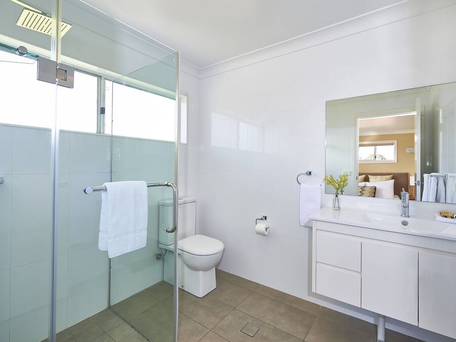 A modern bathroom with a glass shower enclosure, a toilet, and a vanity with a mirror.