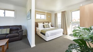 Una habitación de hotel con cama, sofá, escritorio y un ventanal grande.