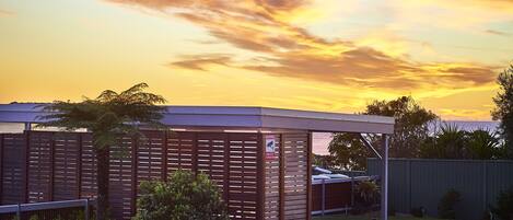 A modern building with a flat roof, surrounded by a well-maintained lawn and a wooden fence.