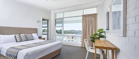 Ein Hotelzimmer mit Bett, Schreibtisch, Stuhl und einem Balkon mit Aussicht.