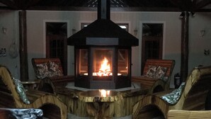 A cozy room with a central wood-burning stove, wooden furniture, and a vaulted ceiling. - Clarence River Bed & Breakfast (Seelands)