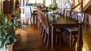 A spacious dining room with a long wooden table, surrounded by chairs, and a staircase leading to an upper level. - Clarence River Bed & Breakfast (Seelands)