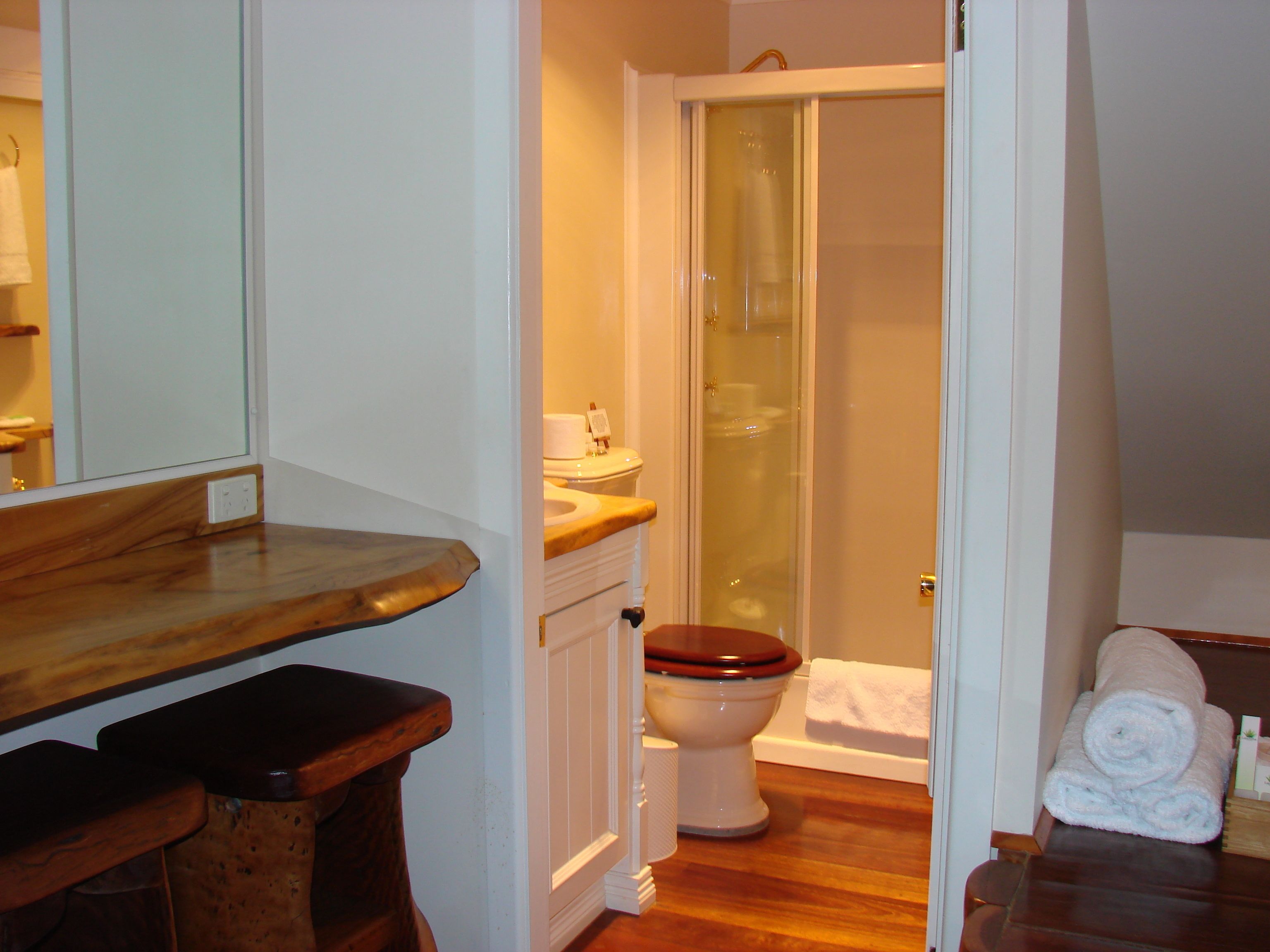 Un baño con tocador de madera, inodoro, cabina de ducha de vidrio y una toalla en el suelo.