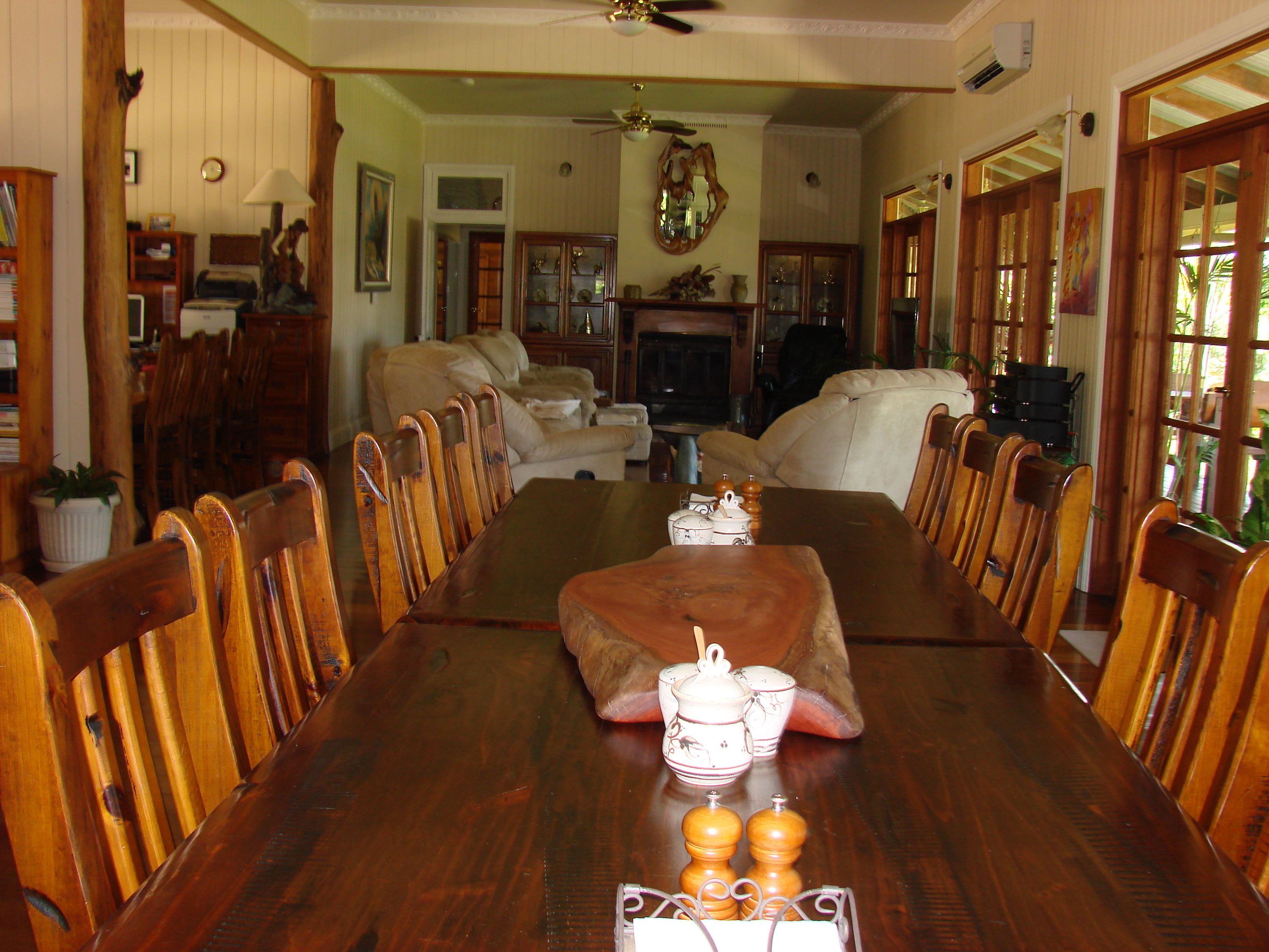 Comedor con una larga mesa de madera dispuesta para cuatro, rodeada de sillas de madera.