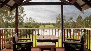A wooden deck with a picnic table and two chairs, overlooking a lake and greenery. - Clarence River Bed & Breakfast (Seelands)