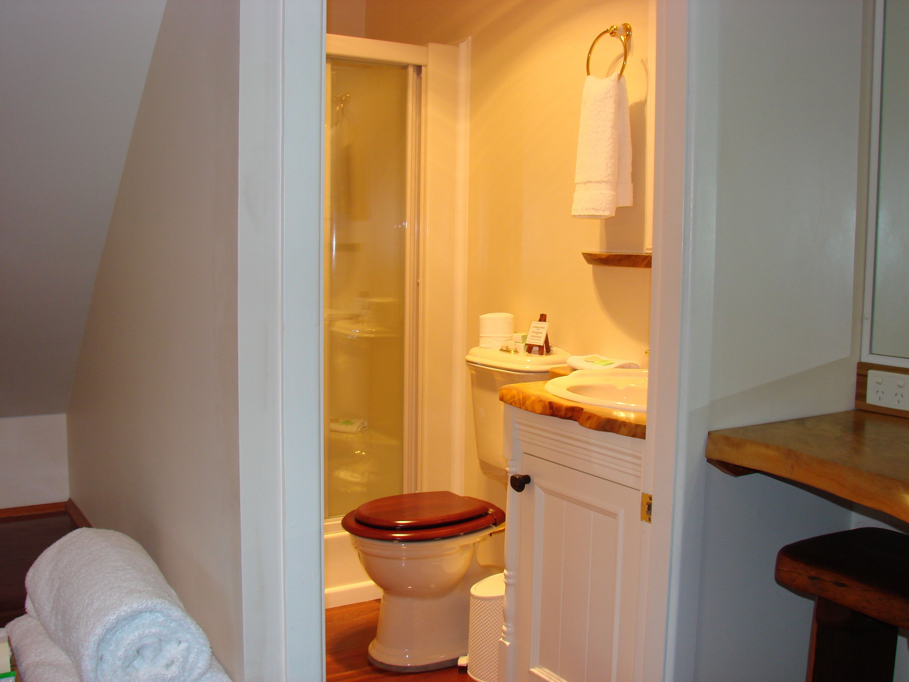 A bathroom with a wooden toilet, a sink with a marble countertop, and a towel rack.