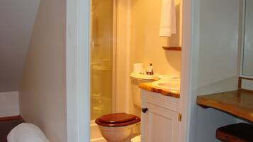 A bathroom with a wooden toilet, a sink with a marble countertop, and a towel rack.