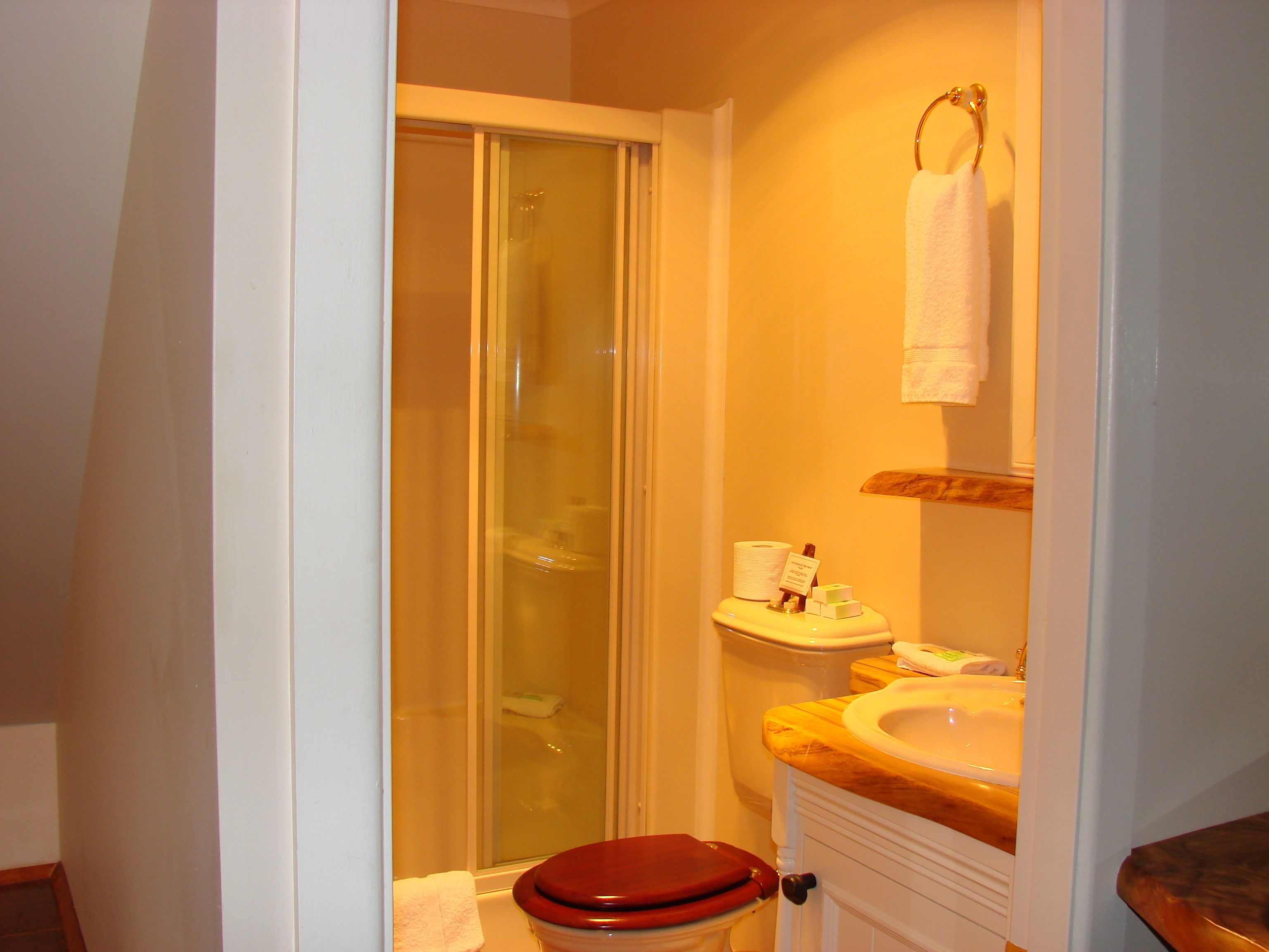 A bathroom with a glass shower enclosure, a wooden vanity with a sink, and a red toilet.