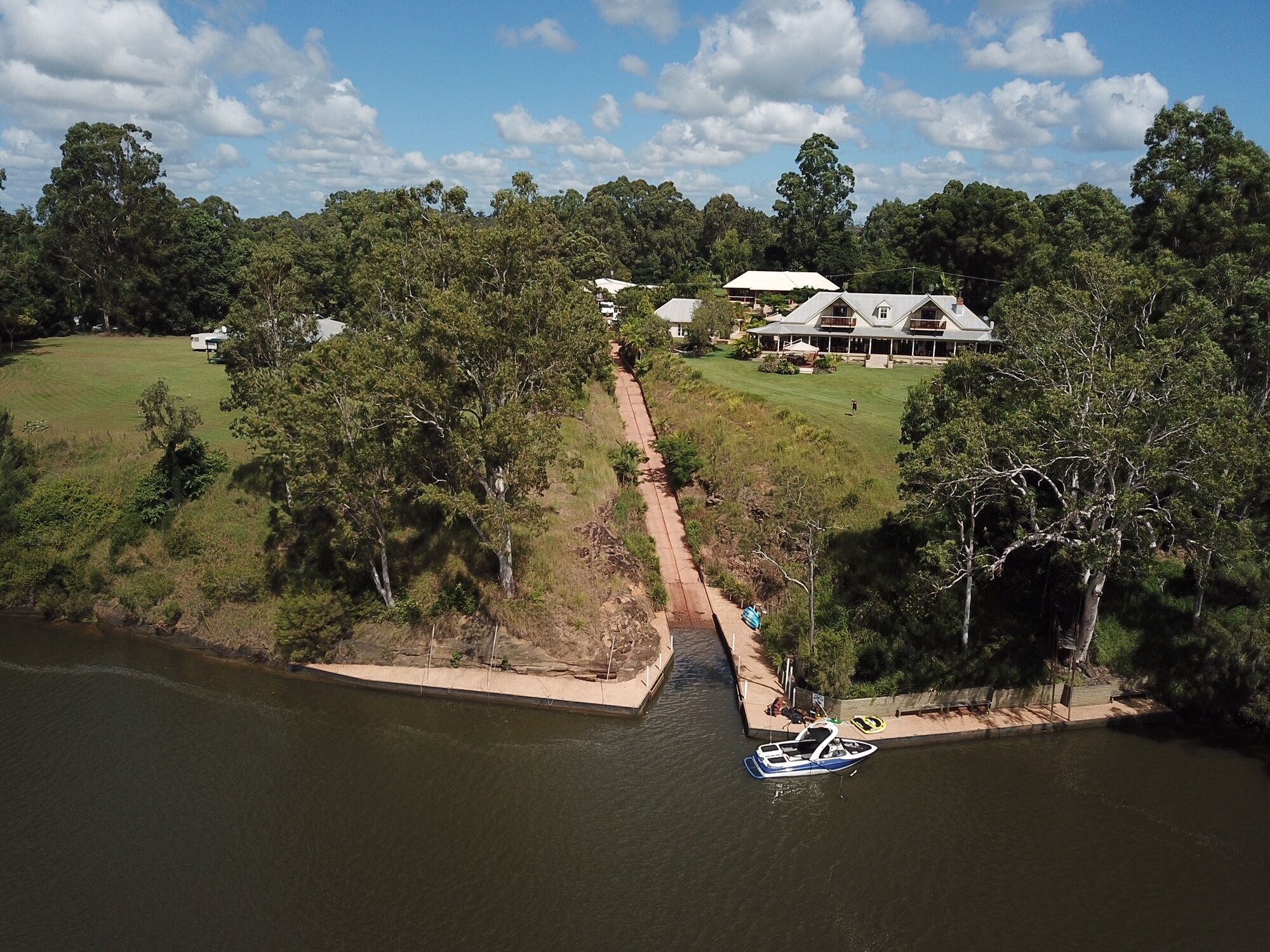 A large house with a lawn and a dock by a lake.