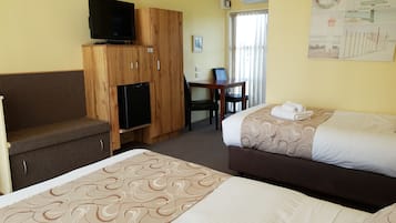 Camera d'albergo con due letti, una scrivania, una sedia, una televisione e un frigorifero.