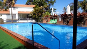 A swimming pool with a clear blue water, surrounded by a brick border and a green artificial turf area. - Moon River Motor Inn (Kempsey)
