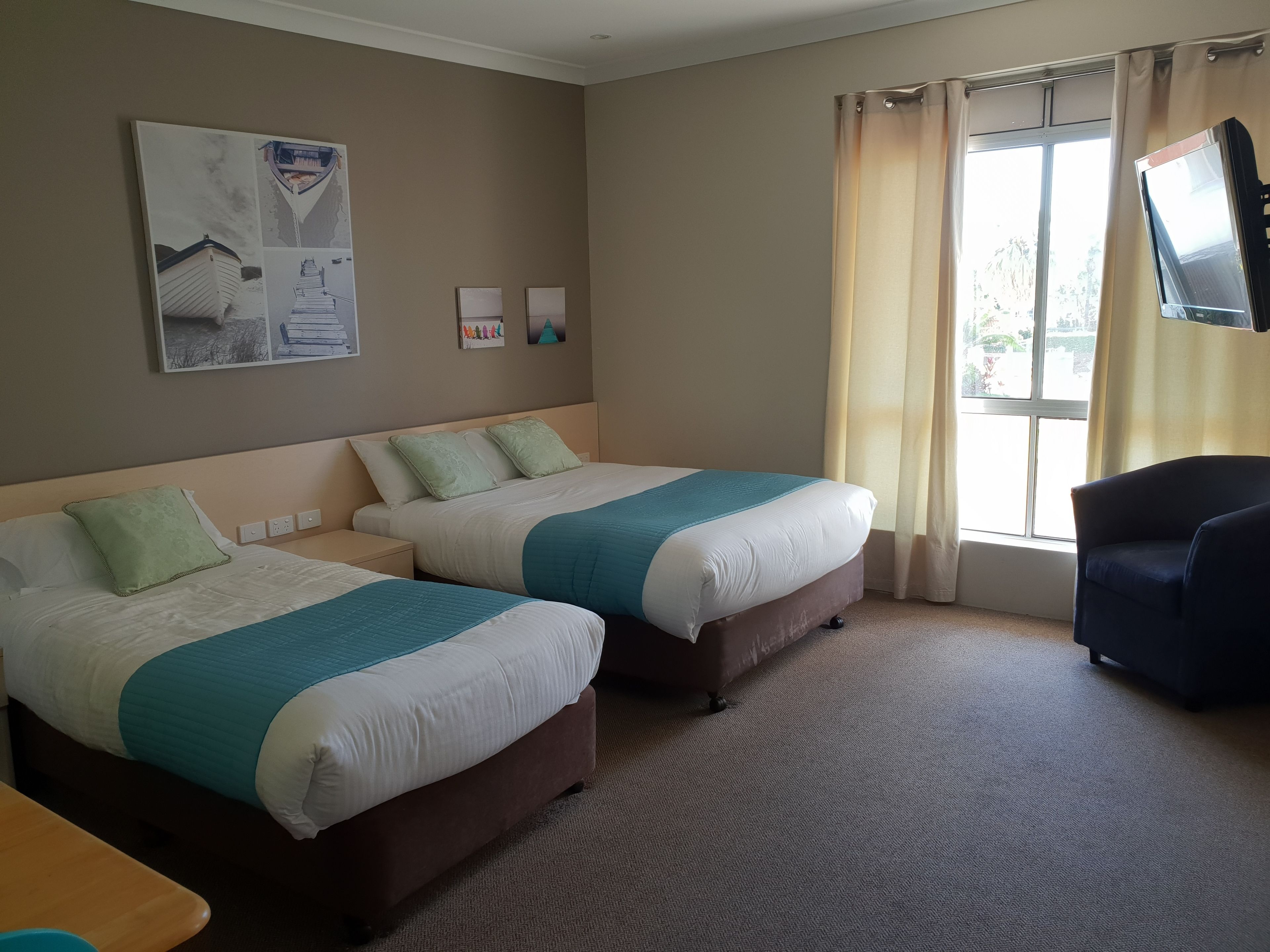 A hotel room with two beds, a TV, and a window with curtains.