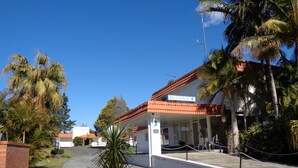 A reception area with a sign, a covered outdoor seating area, and a clear sky. - Moon River Motor Inn (Kempsey)