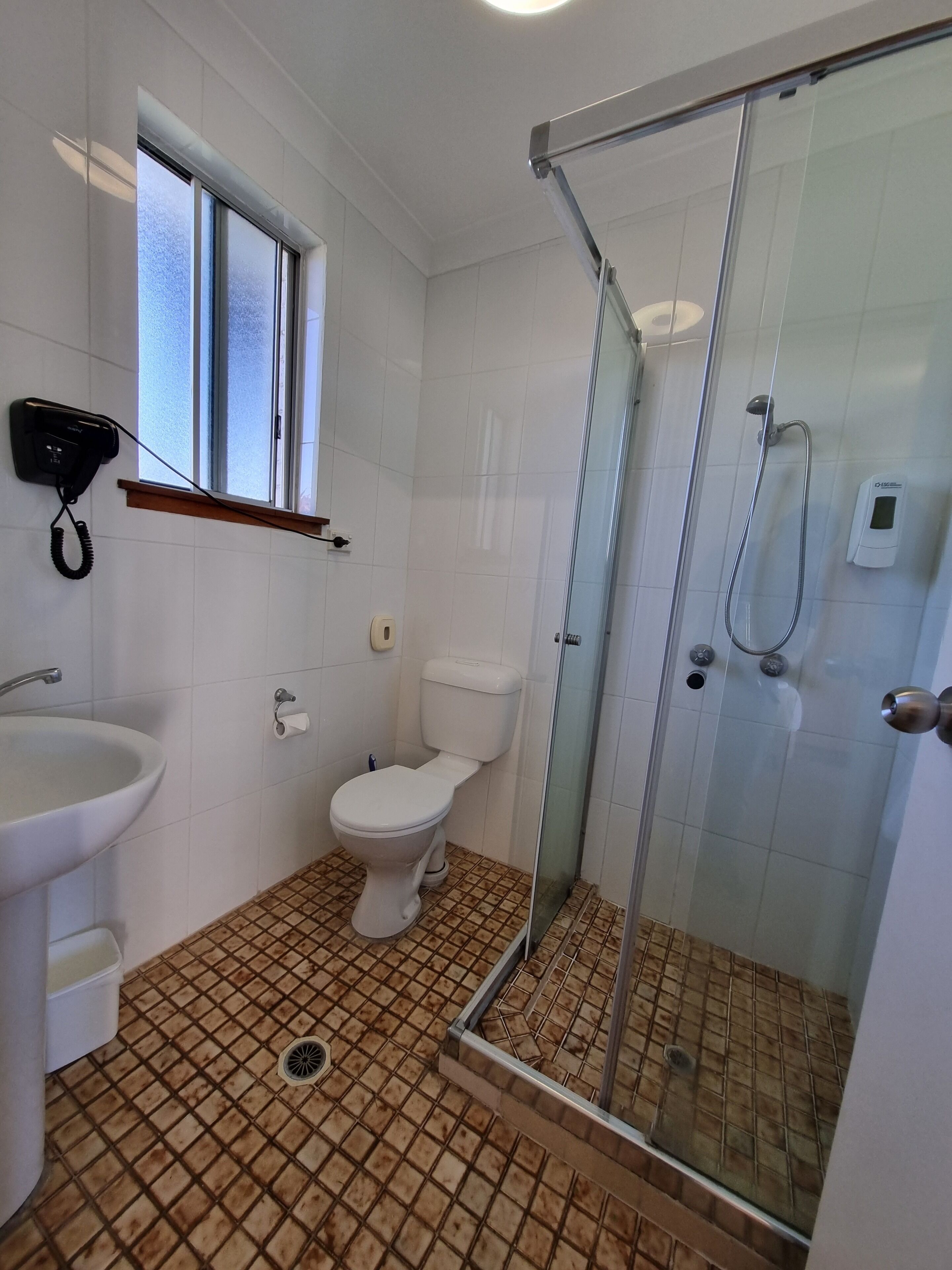 A bathroom with a toilet, sink, and glass-enclosed shower.