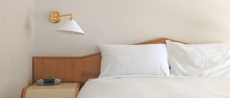 Una habitación de hotel con una cama, una mesita de noche con lámpara y un radio.