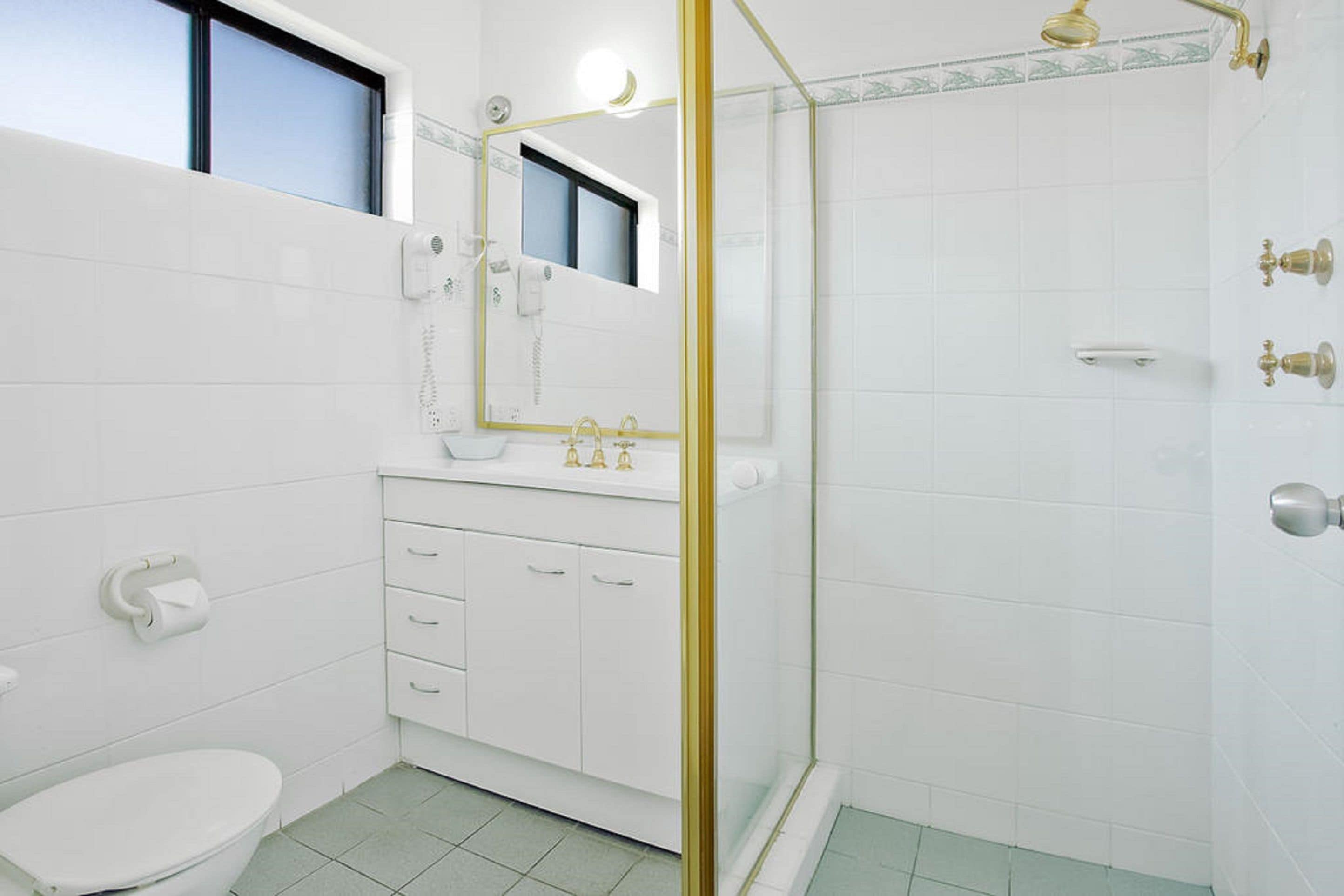A bathroom with a toilet, sink, and shower.