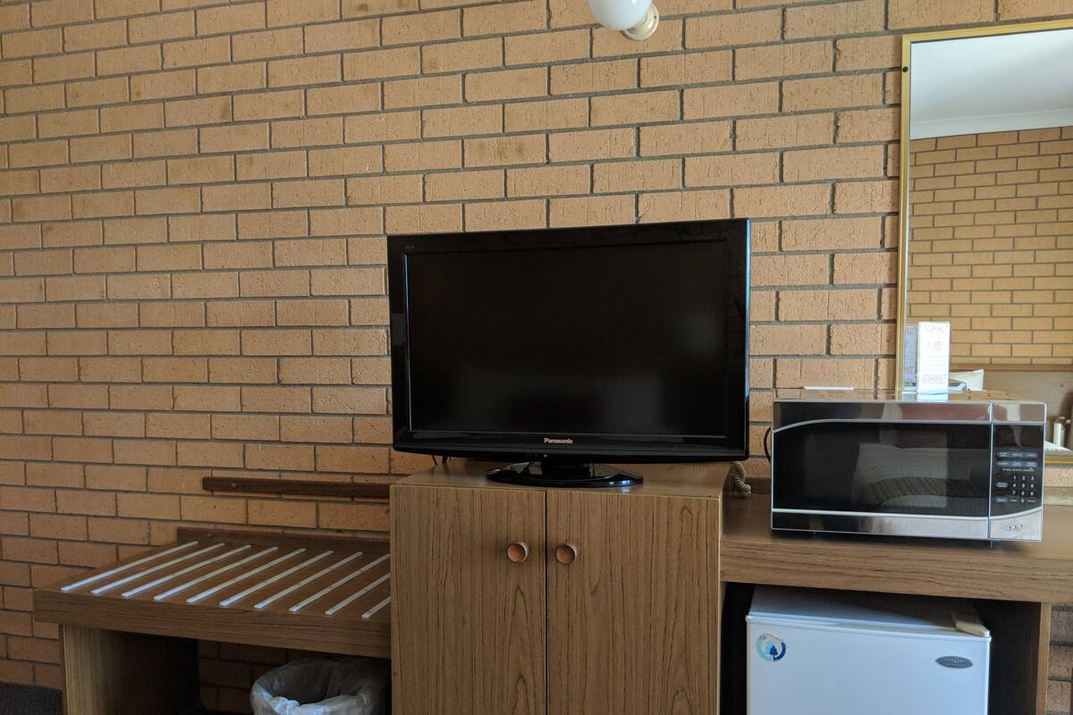 A kitchenette with a television, microwave, and refrigerator.