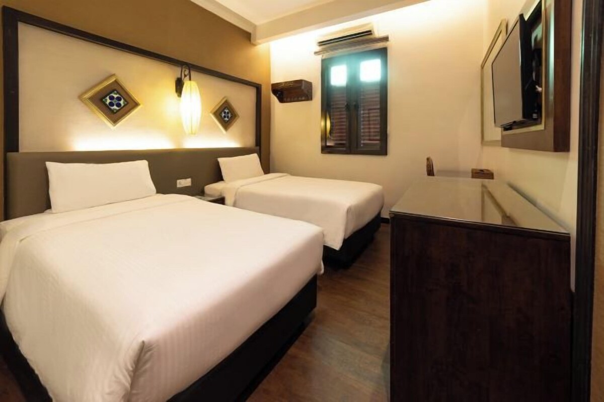 A hotel room with two beds, a large mirror, and a wooden dresser.