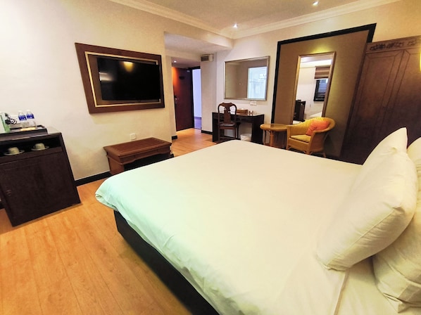 Habitación de hotel con cama, escritorio, silla, televisión y minibar.