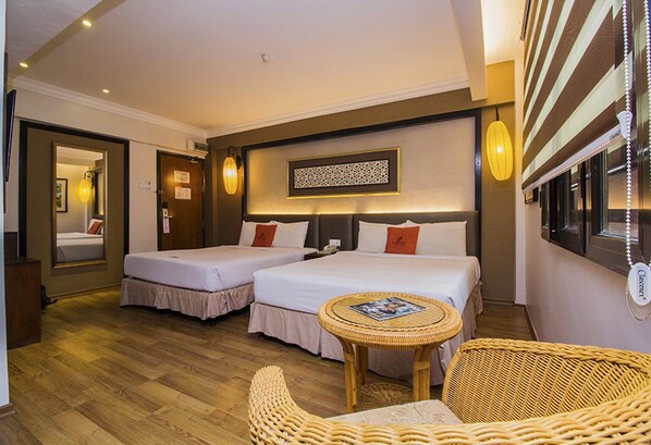 A hotel room with two beds, a small round table, wicker chairs, and a decorative wall piece. - Puri Melaka (Malacca City)