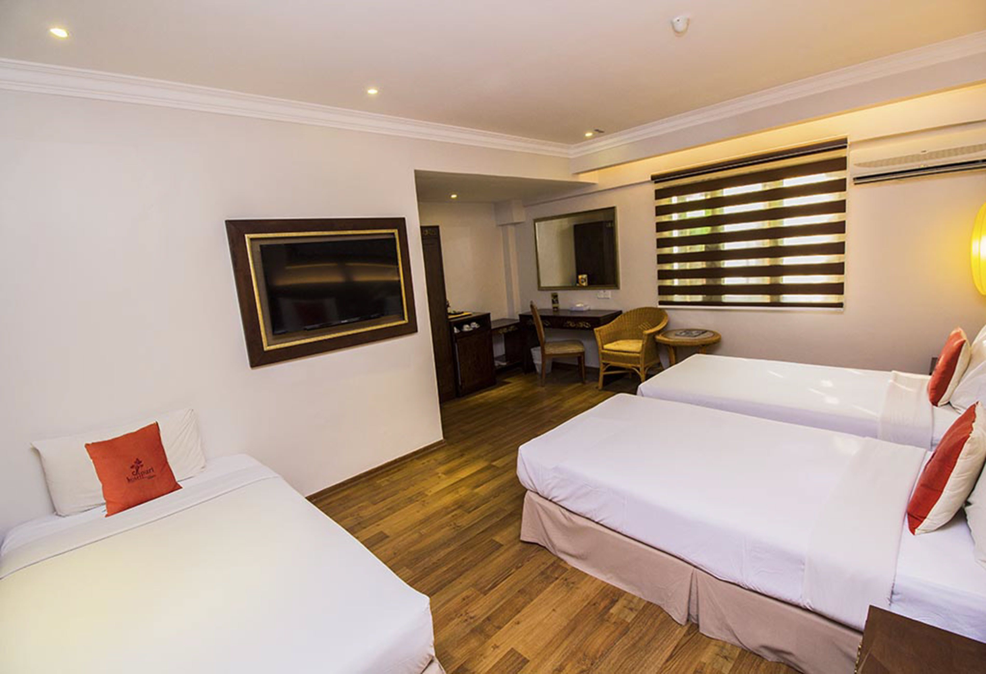 Habitación de hotel con dos camas, un escritorio, una silla y un espejo.