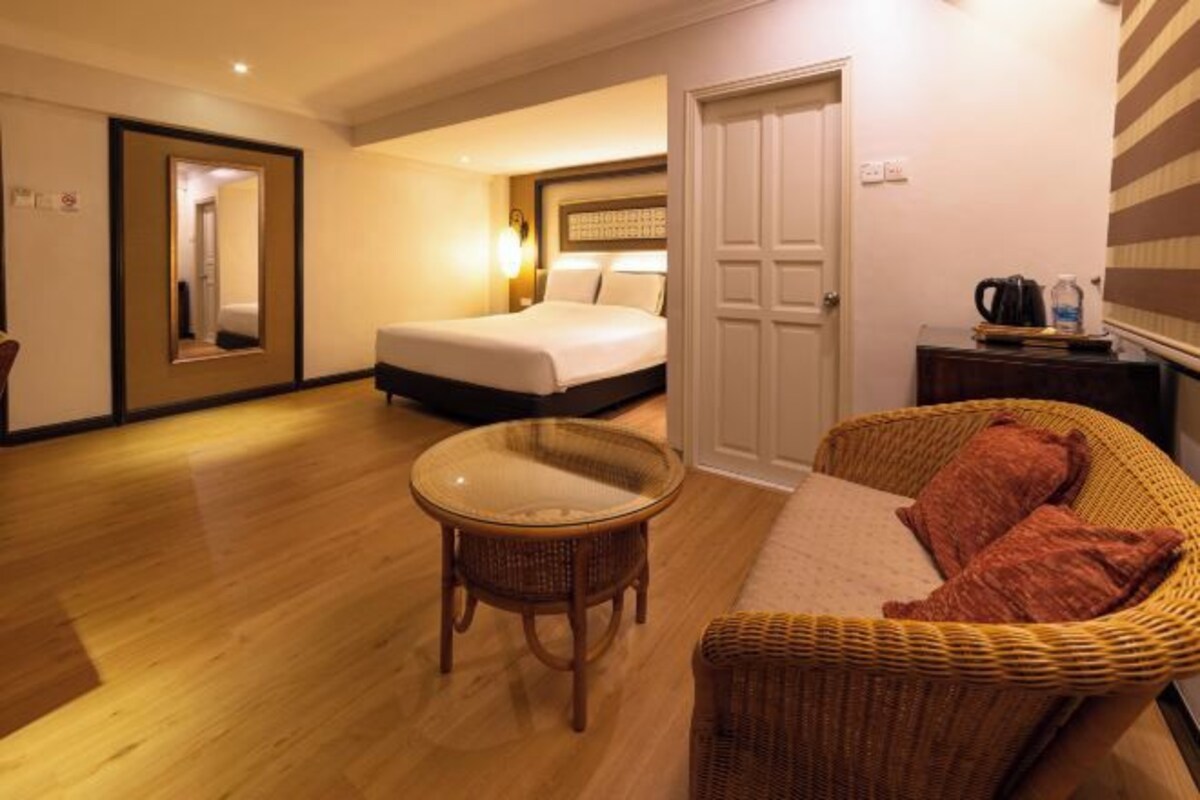 A hotel room with a bed, a round table, a wicker sofa, and a door.