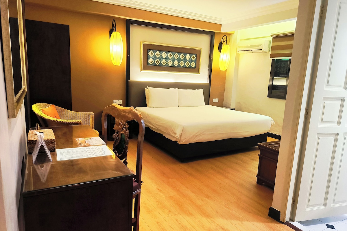 A hotel room with a bed, bedside tables, a lamp, a wall-mounted artwork, and a wooden floor.