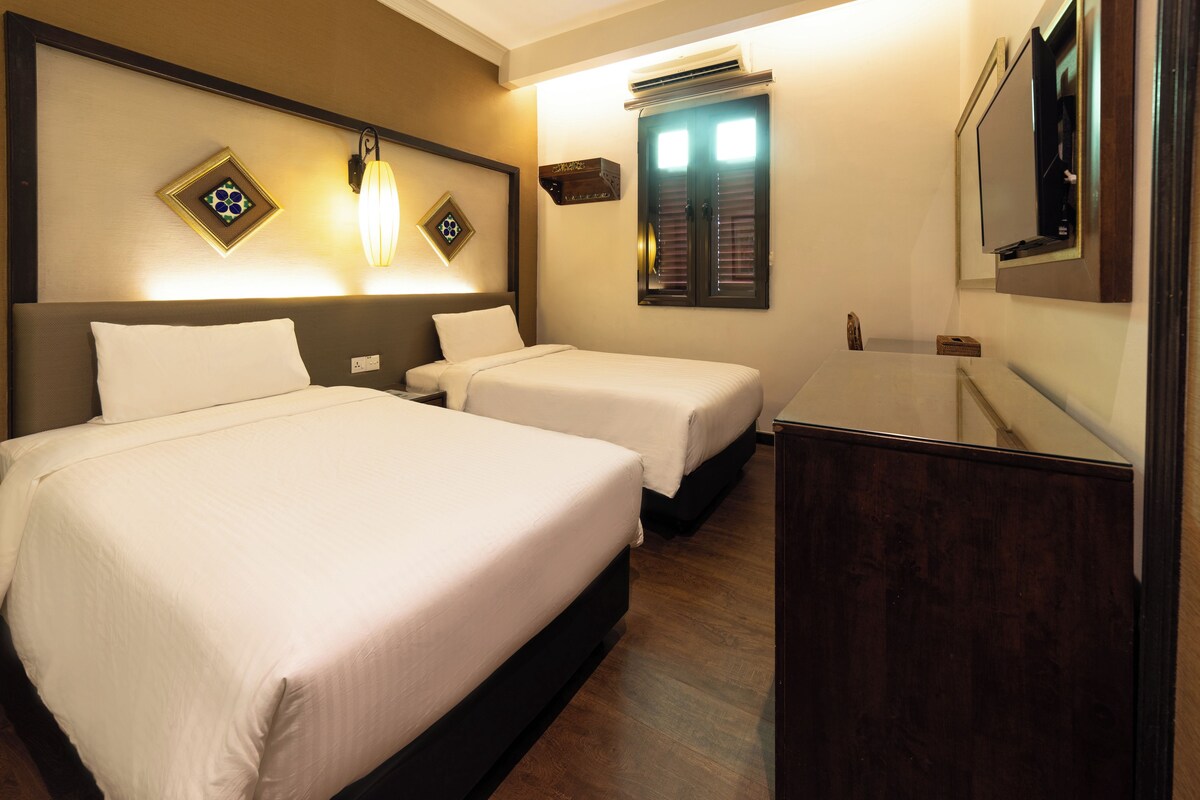 A hotel room with two beds, a nightstand, a mirror, and a wall-mounted air conditioning unit.