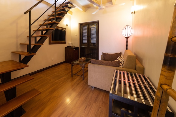 A living room with a wooden staircase, a sofa, a coffee table, and a lamp.