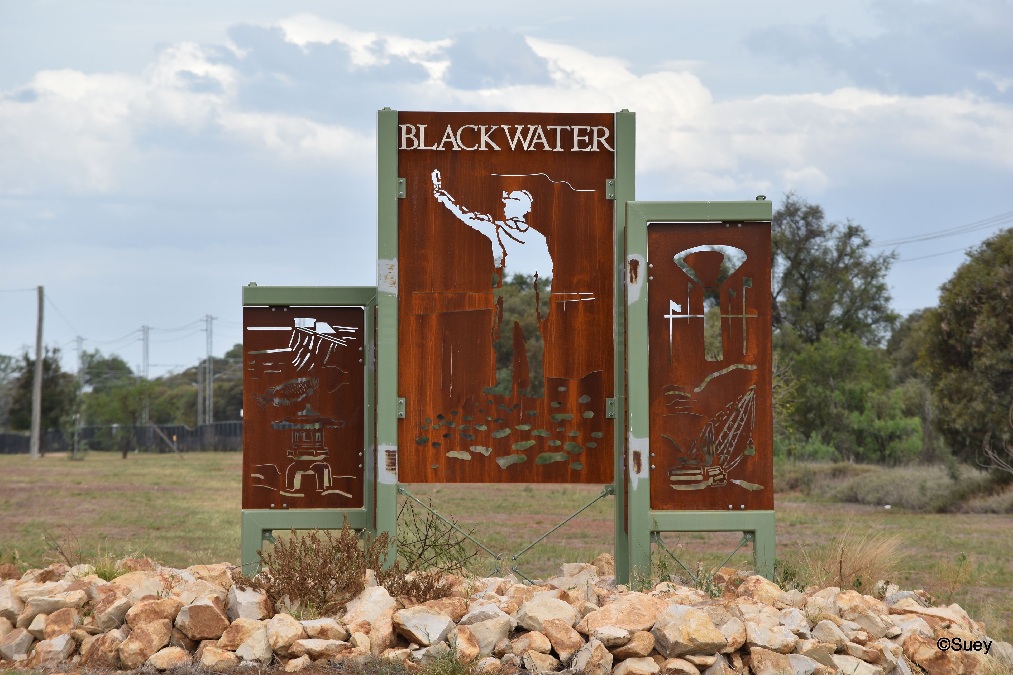 A metal sign with the text "BLACKWATER" and illustrations of a person taking a photo, a fish, and a diver.