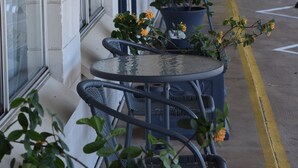 A covered outdoor seating area with tables and chairs, potted plants, and a yellow line marking the edge of the pavement. - Black Diamond Motel (Blackwater)