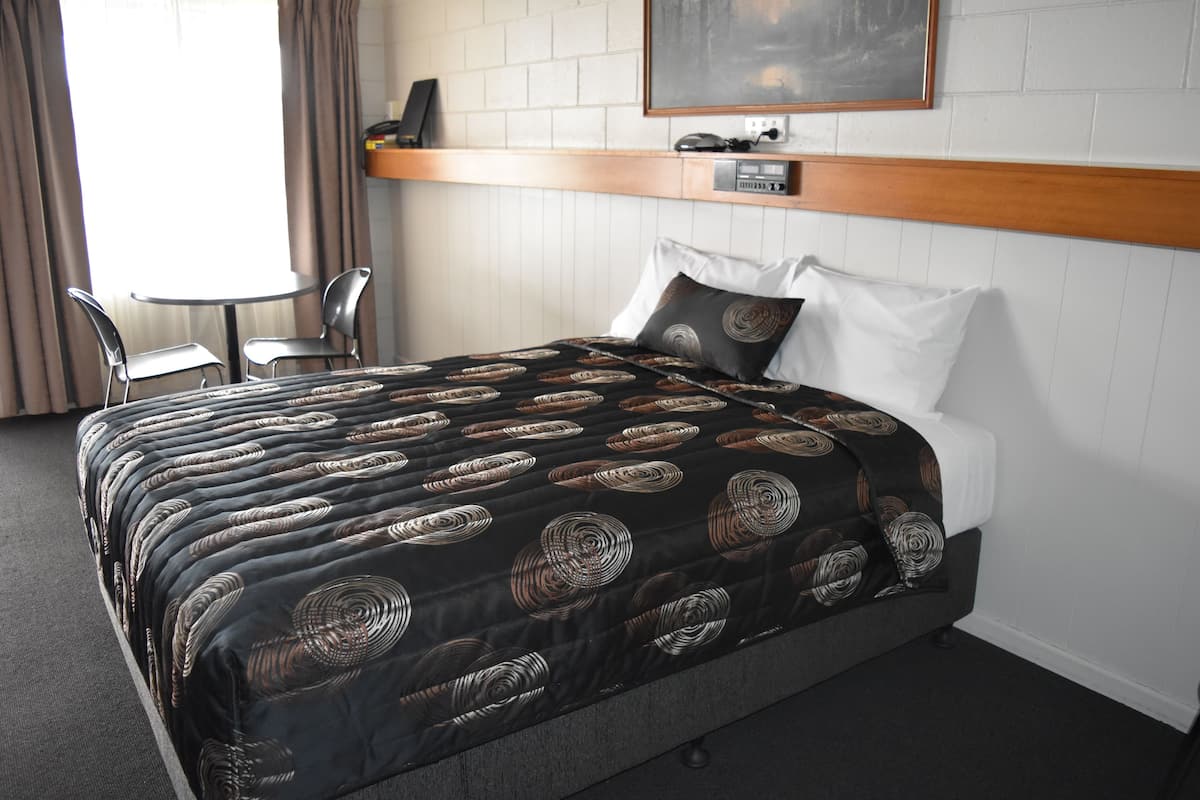 Ein Hotelzimmer mit Bett, Schreibtisch und Stuhl.