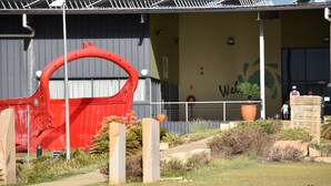 A building with a large red sculpture in front, a sign that says "Welcome," and a potted plant on the steps. - Black Diamond Motel (Blackwater)