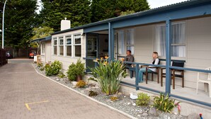 A building with a covered porch, a car parked in front, and various plants along the walkway. - Seagulls Guesthouse (Tauranga)