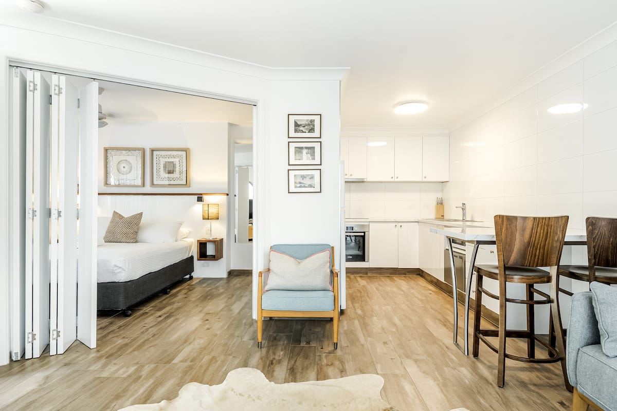 Un espacio habitable moderno y abierto con una cama, zona de estar y cocina.