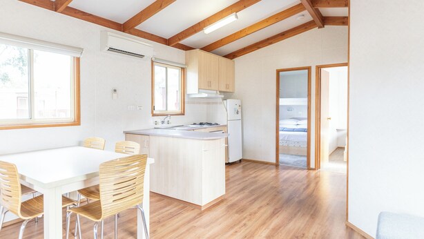 Eine geräumige Küche mit Holzbalken, einem Essbereich mit Stühlen und einem großen Fenster.
