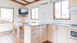 Eine moderne Küche mit Holzausstattung, einer eingebauten Mikrowelle und einem Essbereich mit Tisch und Stühlen.