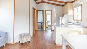 Eine geräumige Küche mit Holzbalken, einem Essbereich und einem sichtbaren Schlafzimmer mit Bett und Schminktisch.
