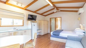 Ein kleines Zimmer mit Küchenzeile, einem Bett, einem Schlafsofa und einem Fernseher.