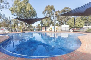 Una piscina al aire libre, sillones reclinables de piscina