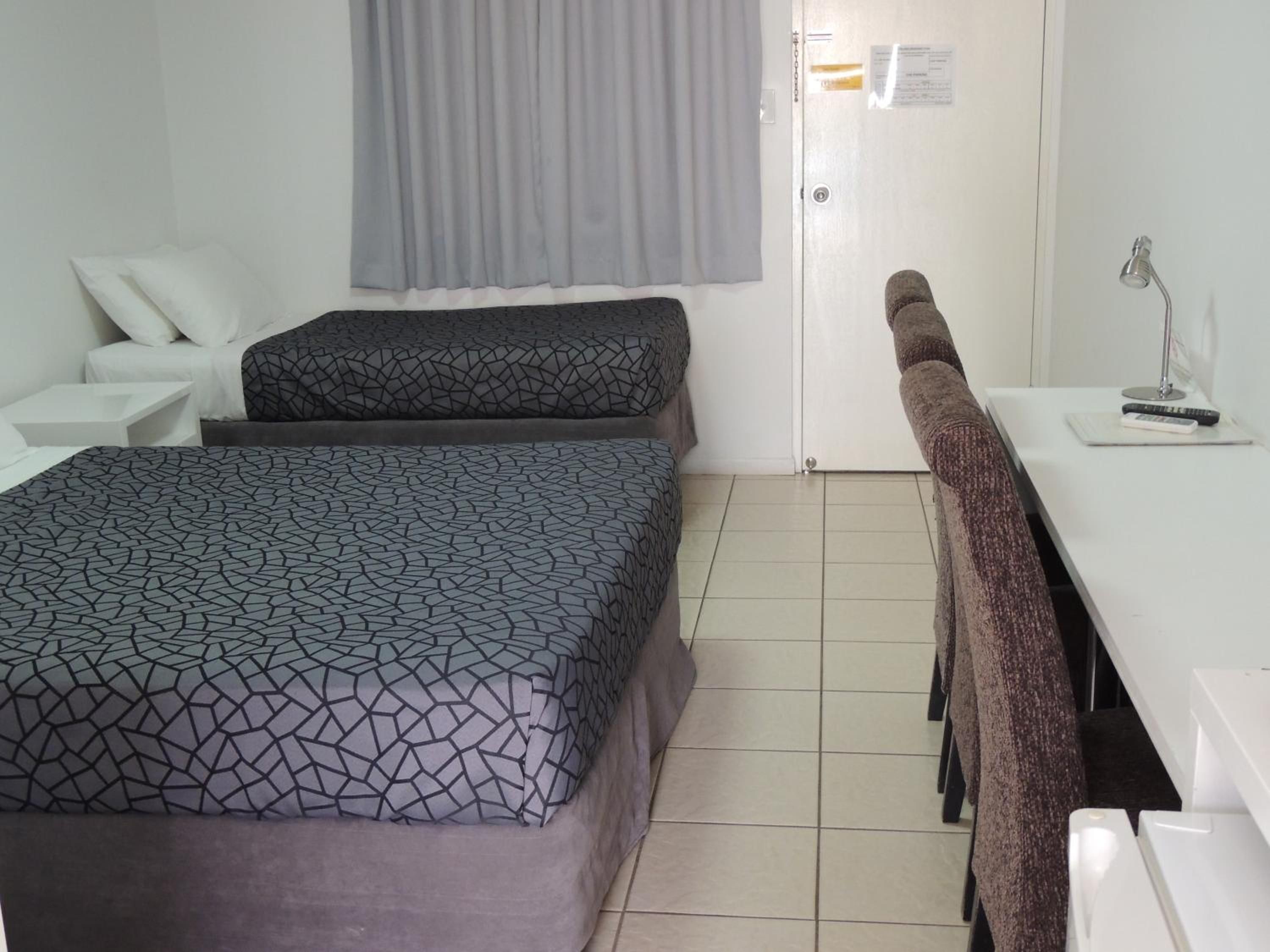 Una habitación de hotel con cama, escritorio, silla y zona de ducha.